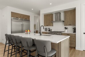 Eine moderne Küche mit einer zentralen Kochinsel, Edelstahlgeräten und Holzschränken.