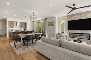 A modern living room with a fireplace, a dining area, and a kitchen. - Courtside Sunsets: Near Pickleball Courts and Pool (St. George)