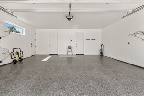 Ein geräumiger, leerer Raum mit einem gefleckten Boden, weißen Wänden und einer Projektor-Decke.