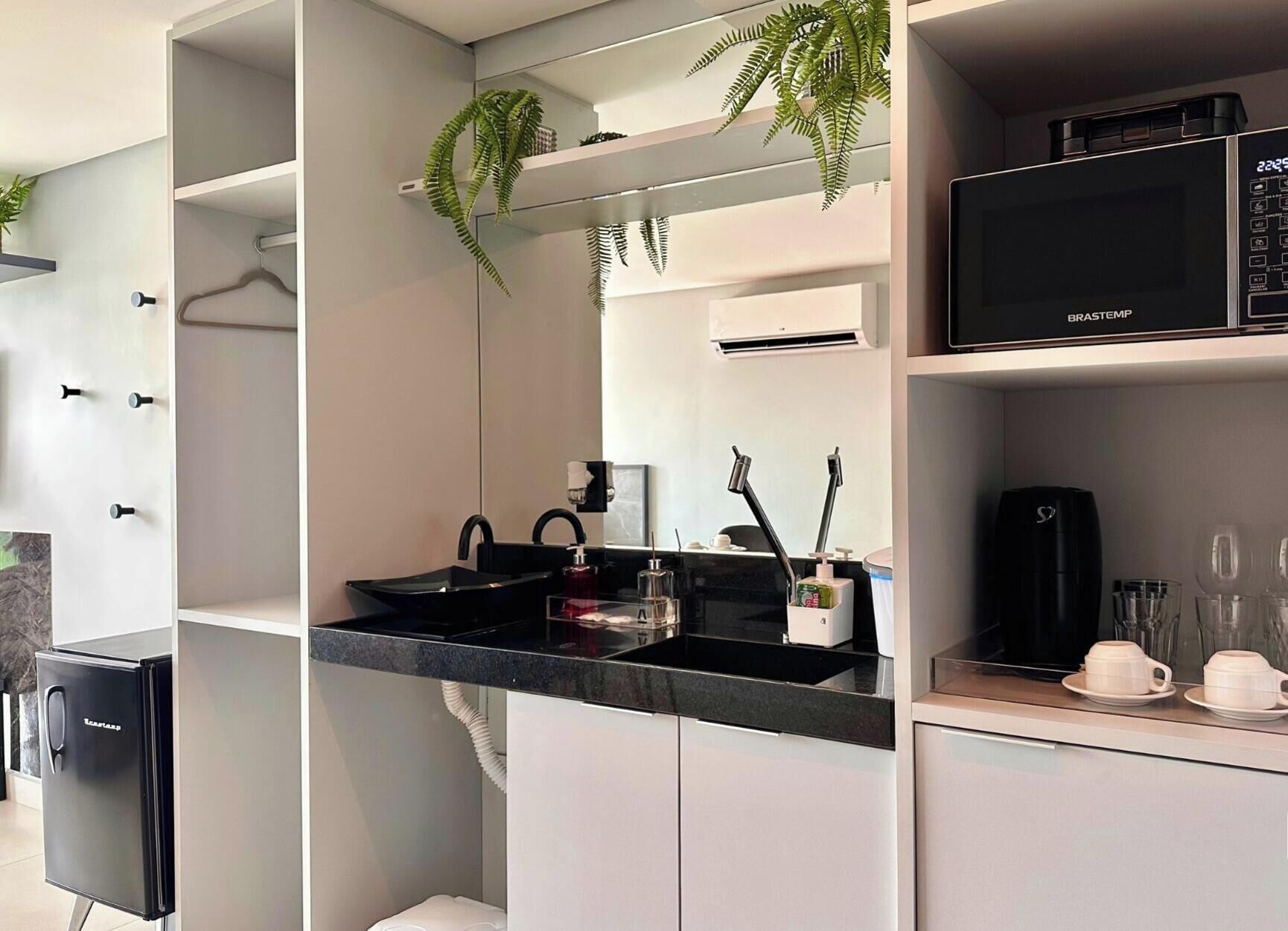 A modern kitchen with a black refrigerator, a microwave, and a sink with a black countertop.
