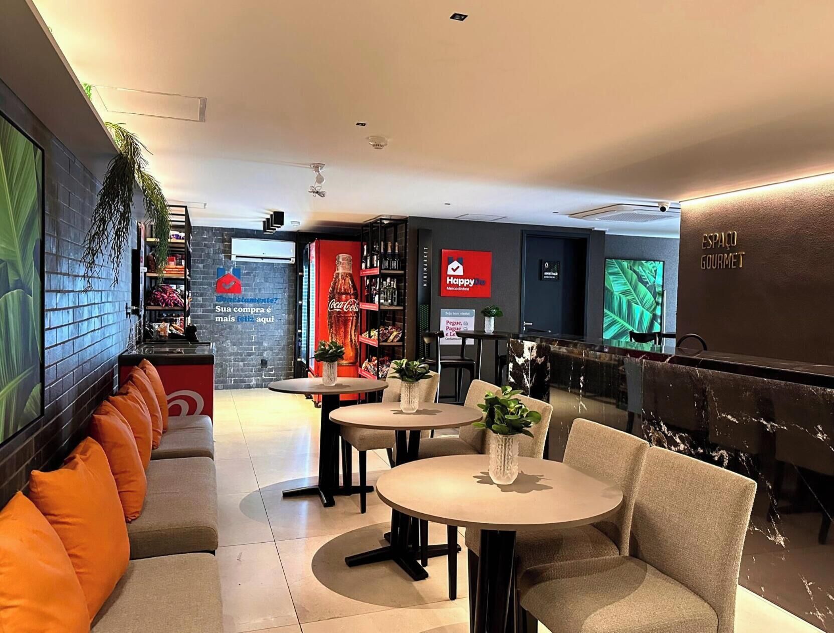 A modern interior with seating areas, tables, and a Coca-Cola branded refrigerator.