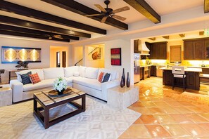 A modern living room with a white sectional sofa, a coffee table, and a ceiling fan. - 4BR Medano Beach Penthouse | Pools, Beach Club & Walk to Town (Cabo San Lucas)