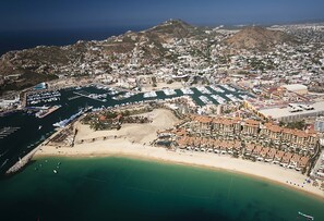 An aerial view of a coastal city with a marina, beachfront hotels, and residential areas. - 4BR Medano Beach Penthouse | Pools, Beach Club & Walk to Town (Cabo San Lucas)