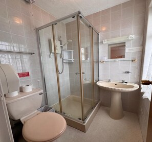 Ein Badezimmer mit Duschkabine, Toilette, Waschbecken und Handtuchhalter.