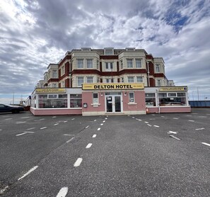 Ein mehrstöckiges Hotel mit einem gut sichtbaren Schild, auf dem 'DELTON HOTEL' steht, und einer Website-Adresse.