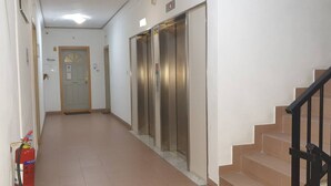 A hallway with a fire extinguisher, an elevator, and a staircase. - Enjoy a comfortable stay in this modern 1-bedroom apartment in Sliema, Malta. Featuring a spacious living area, private bedroom, equipped kitchen and bathroom, it is an ideal base for couples, solo travellers or business stays. (Tas-Sliema)
