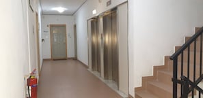 Ein Flur mit Feuerlöscher, Aufzug und Treppe.