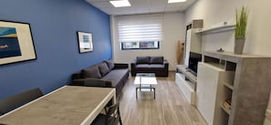 Ein moderner Arbeitsbereich mit Essbereich, Sofas, einem Fernseher und einer Pflanze.