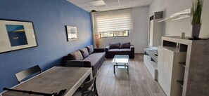 A modern living room with a sofa, a coffee table, and a dining table. - Enjoy a comfortable stay in this modern 1-bedroom apartment in Sliema, Malta. Featuring a spacious living area, private bedroom, equipped kitchen and bathroom, it is an ideal base for couples, solo travellers or business stays. (Tas-Sliema)