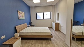 A bedroom with a bed, bedside table, chair, and a window. - Enjoy a comfortable stay in this modern 1-bedroom apartment in Sliema, Malta. Featuring a spacious living area, private bedroom, equipped kitchen and bathroom, it is an ideal base for couples, solo travellers or business stays. (Tas-Sliema)