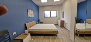 Ein Schlafzimmer mit Bett, Nachttisch, Stuhl und Fenster.
