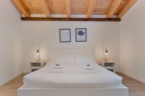 A bedroom with a wooden ceiling, a large bed with white linens, two bedside tables with lamps, and two framed pictures on the wall. - [Il Parco Apartment 8] Natura & Relax-RoadTo5Terre (Beverino)