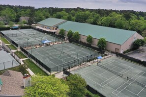 Un grand complexe sportif comprenant plusieurs courts de tennis, un espace de sièges couvert et un bâtiment doté d’un toit végétalisé.