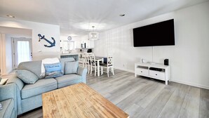 Uma sala de estar moderna com um sofá, mesa de centro e TV fixada na parede.