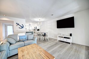 Ein modernes Wohnzimmer mit einer Couch, einem Couchtisch und einem an der Wand befestigten Fernseher.