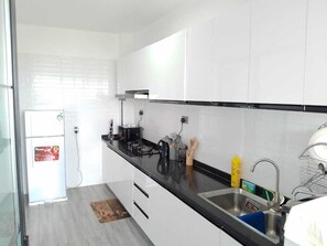 A modern kitchen with white cabinets, a black countertop, and stainless steel appliances. - Staroot - The Velvet Stay (Nairobi)