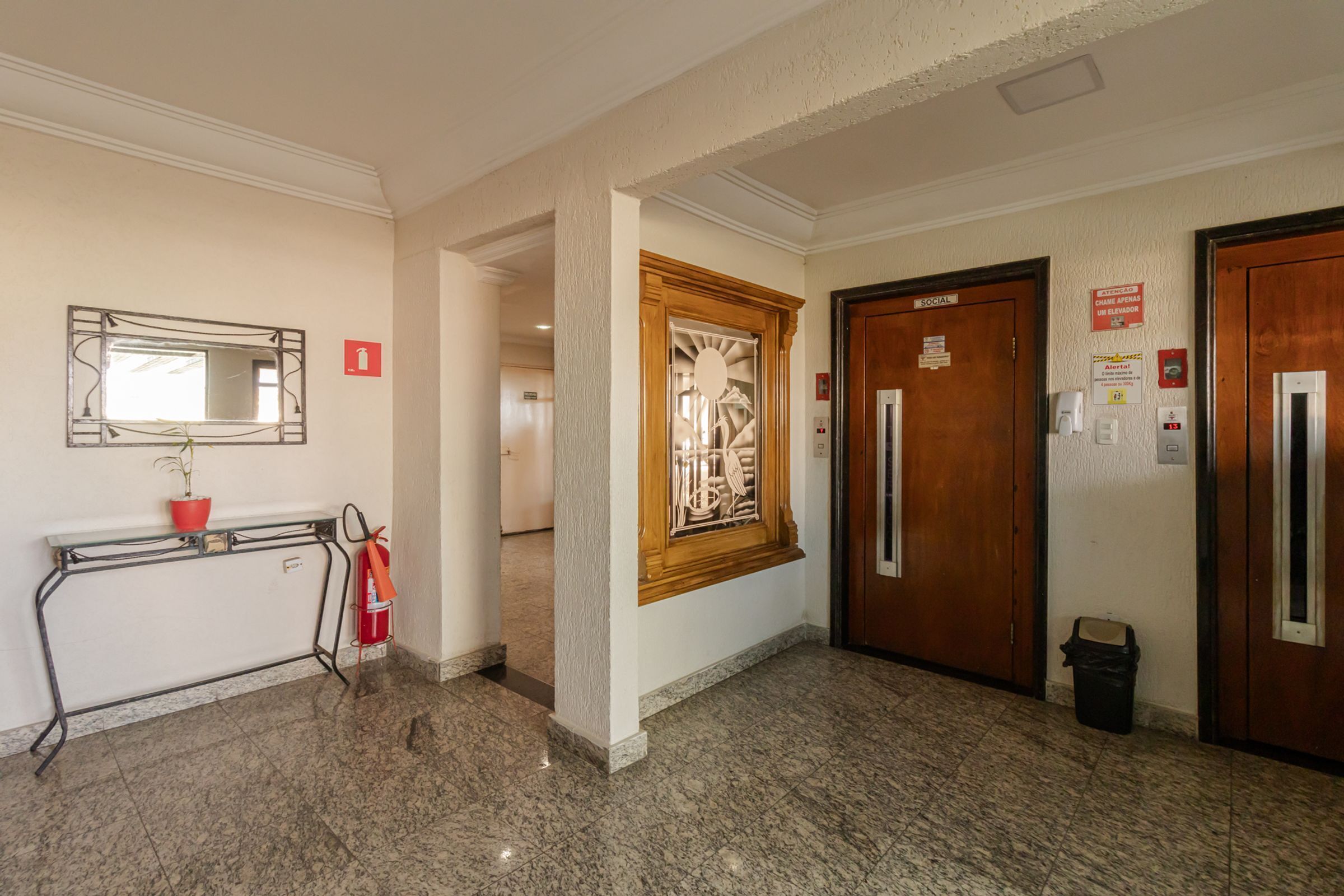 A hallway with a fire extinguisher, a mirror, and two doors labeled 'SOCIAL'.