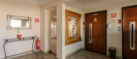 A hallway with a fire extinguisher, a mirror, and two doors labeled 'SOCIAL'.