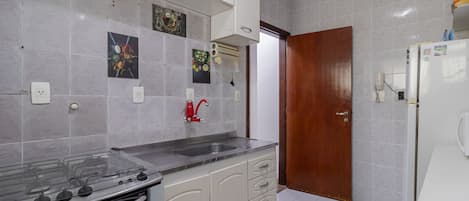Una cocina con estufa, pileta, alacenas y refrigerador.