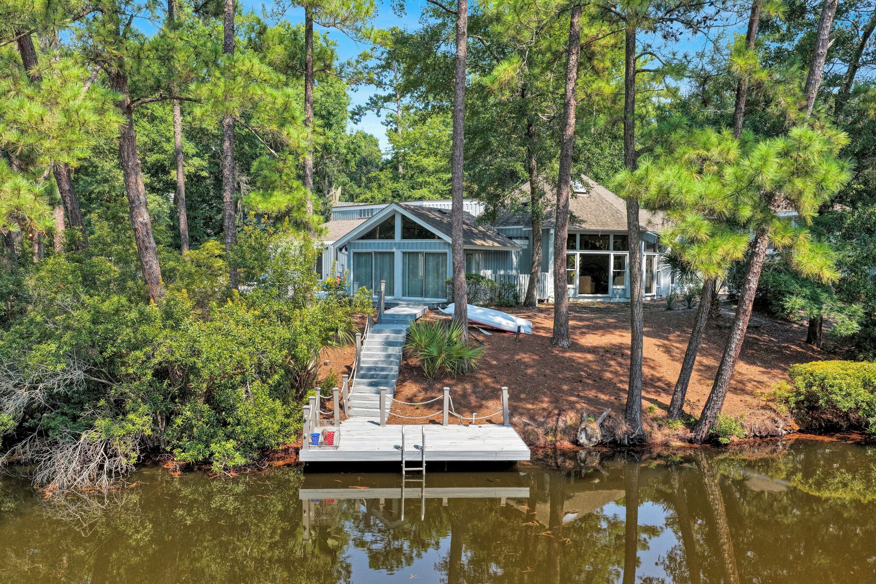 A lakeside cabin with a dock, surrounded by dense trees.