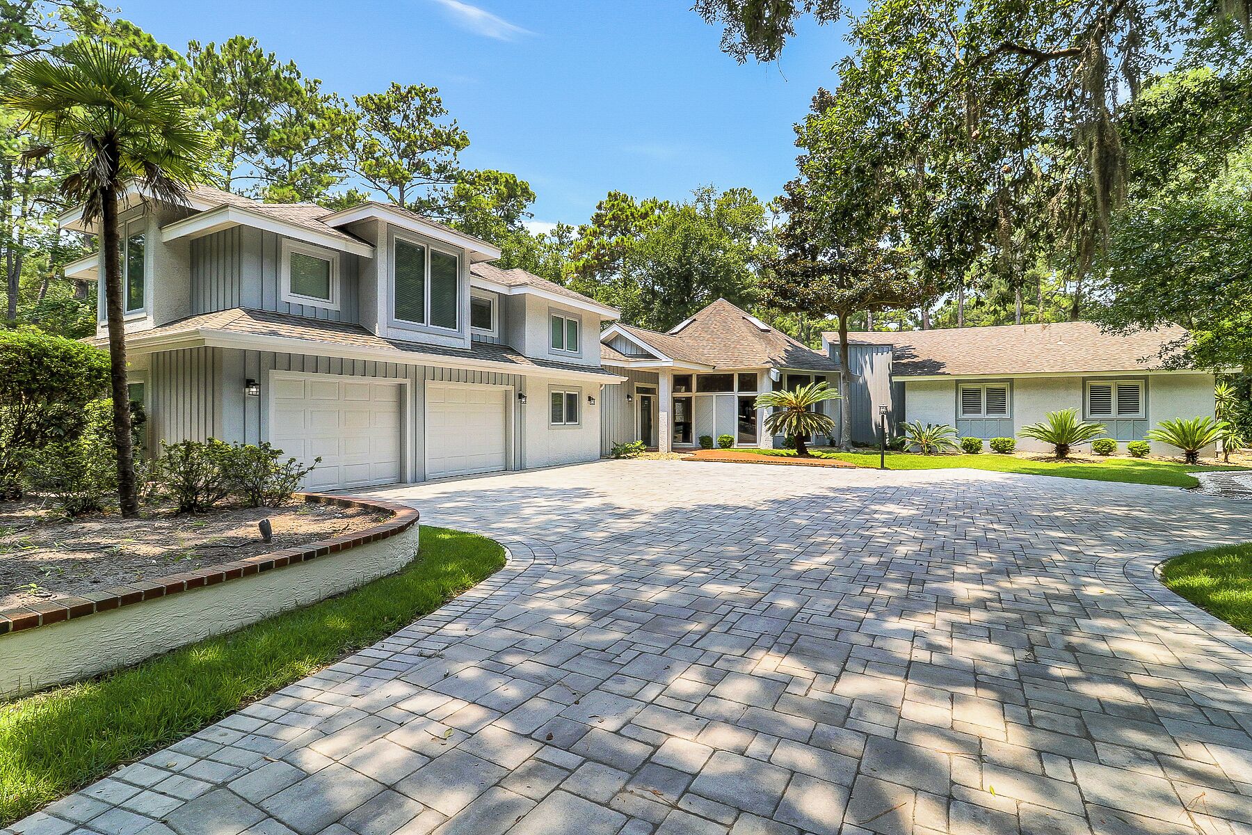 A residential property with a paved driveway, multiple garage doors, and a well-maintained lawn.