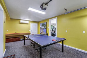 A room with a ping pong table, exercise equipment, and a door. - Huge Home, includes Bikes, Kayaks, Private Pool, Game Room, Dock... (Hilton Head Island)
