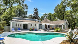 Una propiedad residencial con piscina, mobiliario exterior y un patio cubierto.
