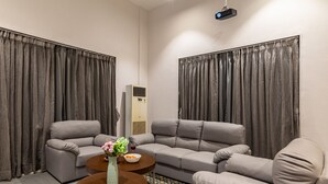 Un salon moderne avec un canapé d’angle, une table basse et un projecteur fixé au plafond.