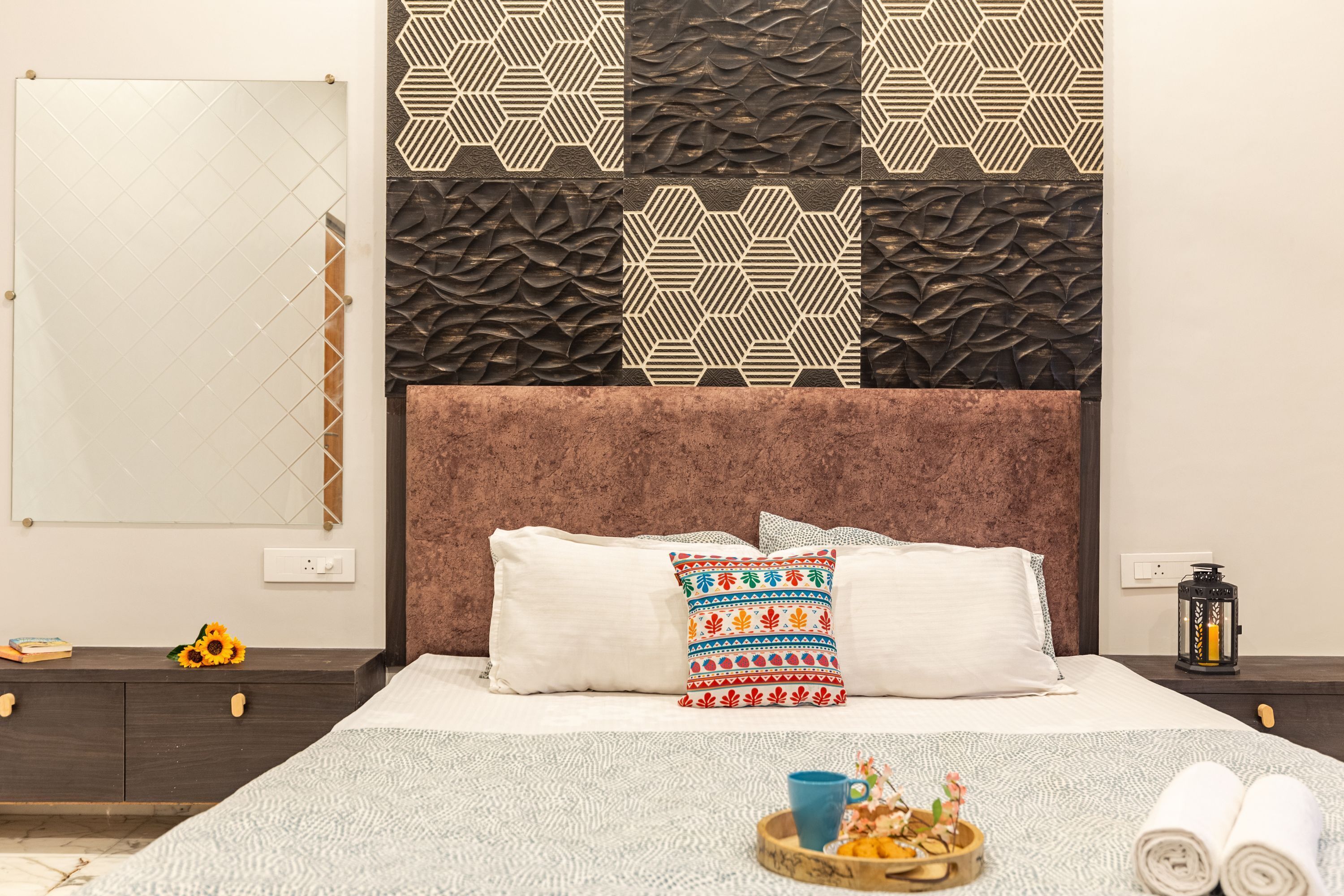 Una habitación de hotel con una cama, una mesita de noche, una lámpara y un panel decorativo en la pared.