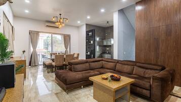 Una sala de estar moderna con un sofá modular, una mesa de centro de madera y un comedor con sillas y una mesa.