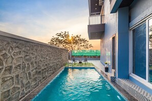A swimming pool with a stone wall on one side and a modern building on the other. - Coastal Cliff (Khandala)
