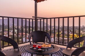 A balcony with wicker chairs, a table, and a tray with food and drinks. - Coastal Cliff (Khandala)