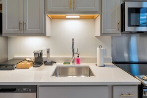 A kitchen with a stainless steel sink, a coffee maker, a dish soap dispenser, and a paper towel holder. - City View Studio - Nearby Parking - Downtown - 3F (Louisville)