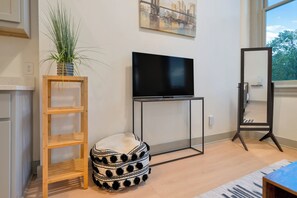 A living room with a TV, a plant, a bean bag, and a mirror. - City View Studio - Nearby Parking - Downtown - 3F (Louisville)