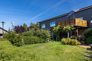 A modern building with a flat roof, large windows, and a covered outdoor area with a wooden deck. - Apartment 'Perle Im Eidertal' with Balcony and Wi-Fi (Pahlen)