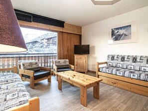 Una sala de estar acogedora con un banco de madera, un sofá y un televisor sobre un mueble.