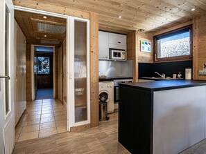 A modern kitchen with wooden accents, a built-in microwave, and a view of a snowy landscape. - Apartment in Morzine center - 4 guests (Morzine)