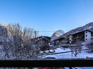 A snow-covered mountain village with traditional wooden buildings, a clear sky, and a prominent mountain peak in the background. - Apartment in Morzine center - 4 guests (Morzine)