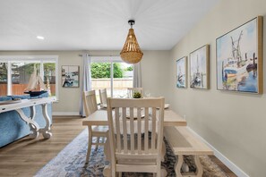 A dining area with a wooden table and chairs, a hanging light fixture, and framed artwork on the walls. - THAT'S WHAT SEA SAID at Seaside Beach (Seaside)
