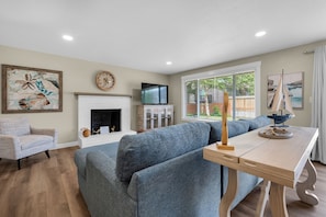 A modern living room with a fireplace, a television, and a dining area with a table and chairs. - THAT'S WHAT SEA SAID at Seaside Beach (Seaside)