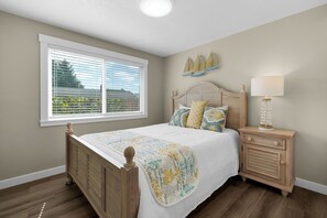 A bedroom with a wooden bed, a nightstand, a lamp, and a window with blinds. - THAT'S WHAT SEA SAID at Seaside Beach (Seaside)