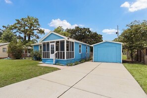 A residential property with a blue house, a covered porch, and a garage. - Escape to this bright, pet-friendly cottage just minutes from Perdido Key's sugar-white sands! Two queen bedrooms sleep 4, plus a full kitchen, in-unit laundry, screened front porch & fenced backyard. Free driveway parking for 4! (Pensacola)