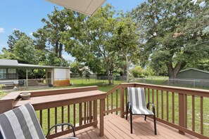 A wooden deck with a railing, a chair, and a table. - Escape to this bright, pet-friendly cottage just minutes from Perdido Key's sugar-white sands! Two queen bedrooms sleep 4, plus a full kitchen, in-unit laundry, screened front porch & fenced backyard. Free driveway parking for 4! (Pensacola)