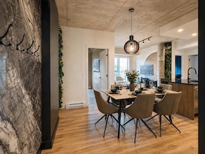 Ein moderner Essbereich mit Marmorwand, Holzboden und einem zentralen Tisch mit Stühlen.