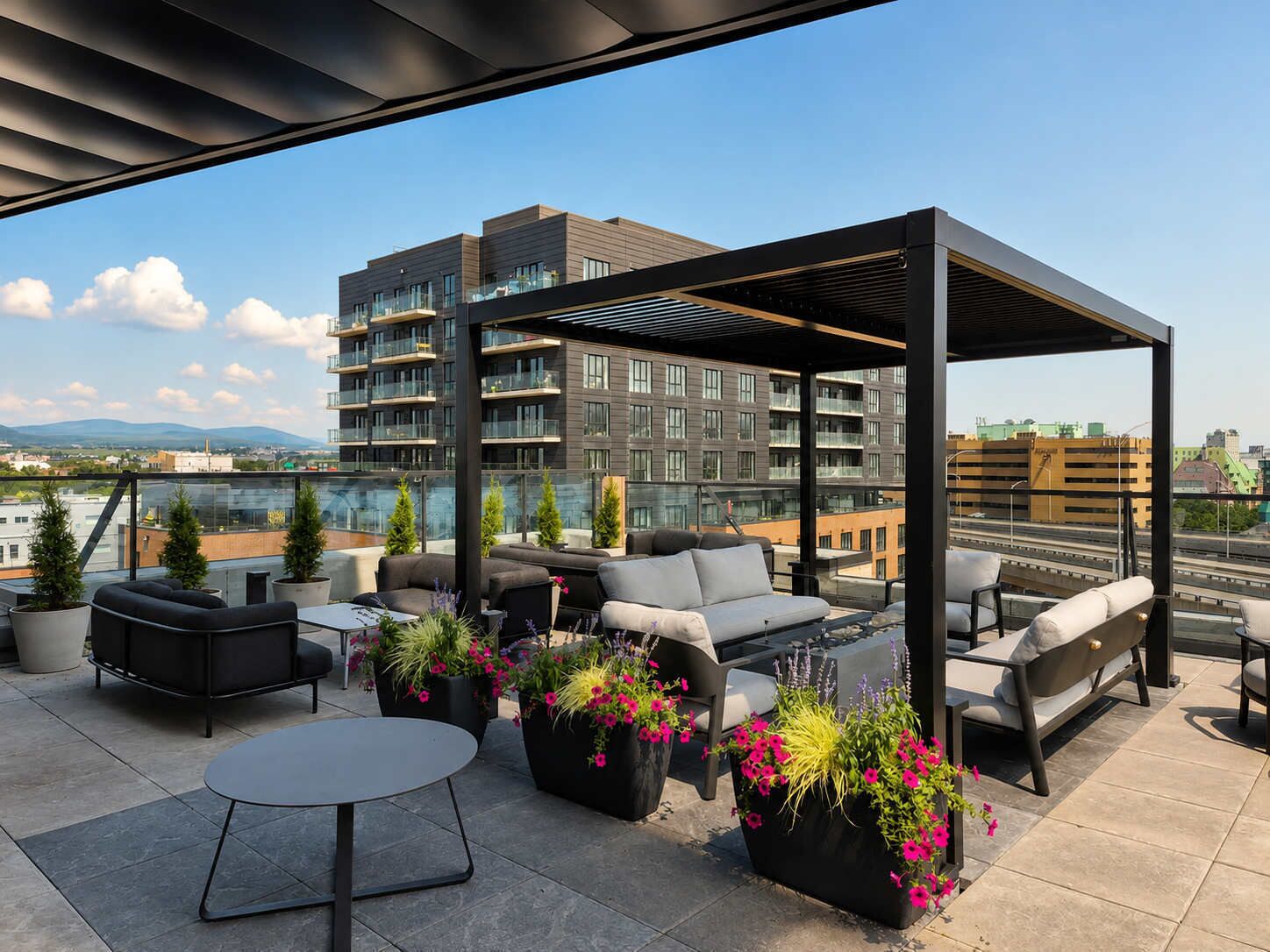Eine Dachterrasse mit Außenbestuhlung, Topfpflanzen und Blick auf eine Stadtlandschaft.