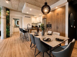 A modern kitchen with wooden cabinets, a built-in microwave, and a central island with bar stools. - Rooftop Pool | Private Terrace | Signature 908 (Québec)