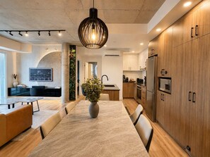 Eine moderne Küche mit Holzausstattung, einer zentralen Kochinsel und einem Essbereich mit Tisch und Stühlen.