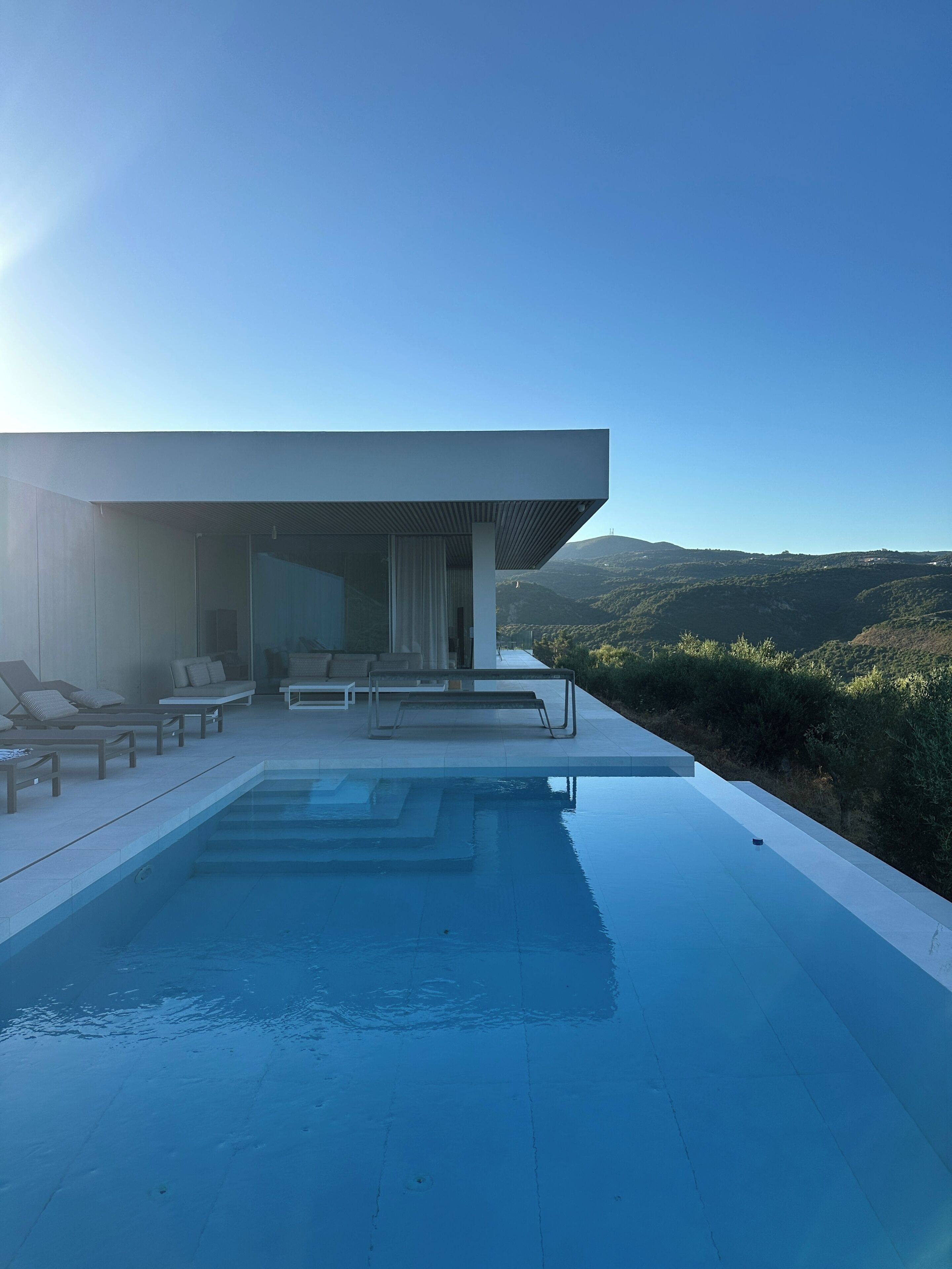Ein moderner Poolbereich mit Liegestühlen und Blick auf die umliegende Landschaft.