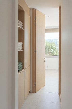 Un couloir avec un placard, une porte donnant sur un balcon et une vue sur les arbres.