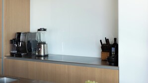 Et moderne køkken med træskabe, kaffemaskine, en vinflaske og en skål med frugt på bordet.
